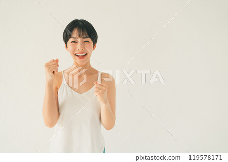 A young woman in a camisole giving a thumbs up in front of a white background A young woman in a camisole giving a thumbs up in front of a white background 119578171