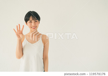身穿吊帶背心的年輕女子在白色背景前做出 4 手勢 119578176