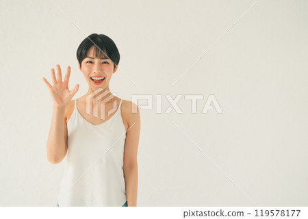 A scene of a young woman in a camisole showing her palm in front of a white background 119578177