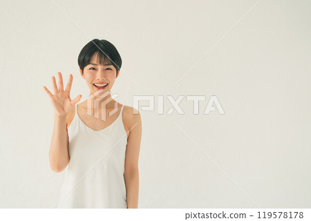 一位身穿吊帶背心的年輕女子在白色背景前展示手掌的場景 119578178