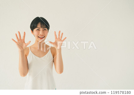 一位身穿吊帶背心的年輕女子在白色背景前展示手掌的場景 119578180