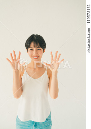 A scene of a young woman in a camisole showing her palm in front of a white background A scene of a young woman in a camisole showing her palm in front of a white background 119578181