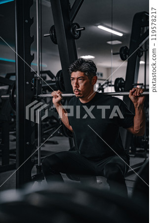 A man in his 40s doing strength training at the gym 119578217