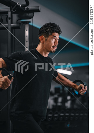 Man using a machine to train at the gym Man using a machine to train at the gym 119578574