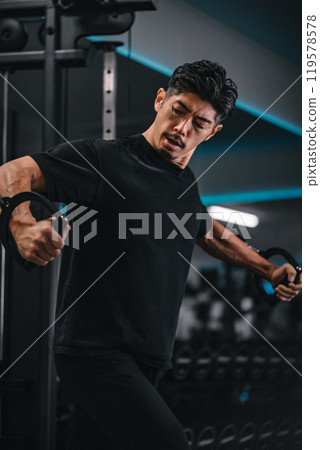 一名男子在健身房使用機器訓練 119578578