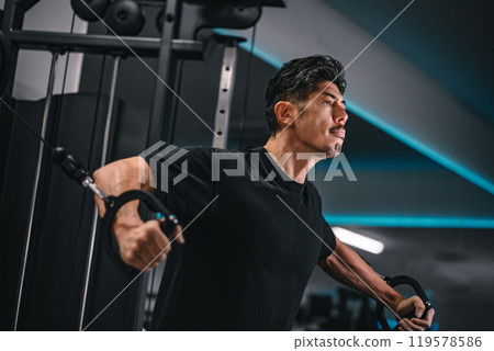 一名男子在健身房使用機器訓練 119578586