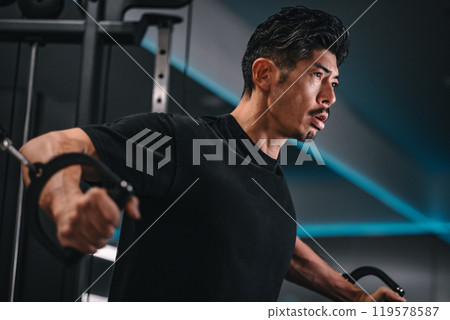 一名男子在健身房使用機器訓練 一名男子在健身房使用機器訓練 119578587