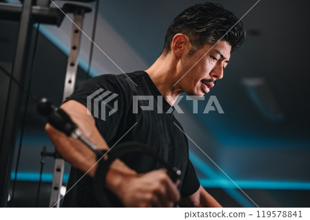 一名男子在健身房使用機器訓練 一名男子在健身房使用機器訓練 119578841
