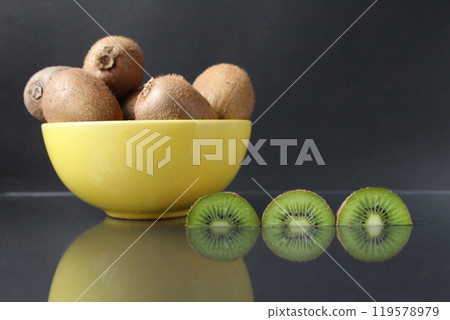still life of kiwi fruit in a yellow bowl plate and pieces of mug next to on a black background with a reflection of there is a copyspace still life of kiwi fruit in a yellow bowl plate and pieces of mug next to on a black background with a reflection of there is a copyspace 119578979