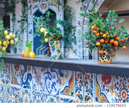 Branch with lemons, tangerines in ceramic vase on table. Traditional pattern, Sicily, Italy. Fruit and decor.  119579043