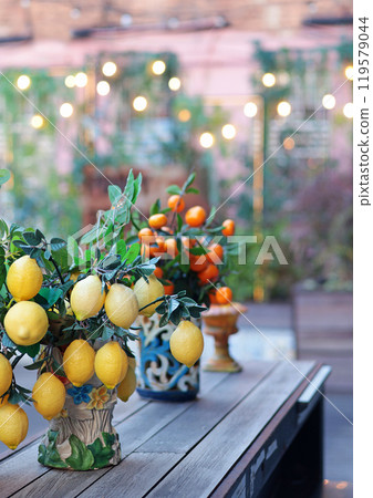 Branch with lemons, tangerines in ceramic vase on table. Traditional pattern, Sicily, Italy. Fruit and decor. Branch with lemons, tangerines in ceramic vase on table. Traditional pattern, Sicily, Italy. Fruit and decor. 119579044