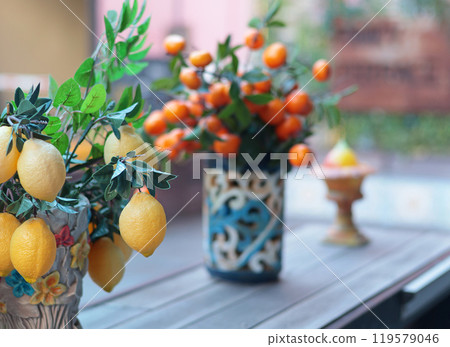 Branch with lemons, tangerines in ceramic vase on table. Traditional pattern, Sicily, Italy. Fruit and decor.  119579046