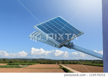 Mini solar cell panel and hd floodlight panal installed together under house eaves to store and use the power from the sunlight with street light and bulbs at night, sunset background, soft focus. Mini solar cell panel and hd floodlight panal installed together under house eaves to store and use the power from the sunlight with street light and bulbs at night, sunset background, soft focus. 119579352