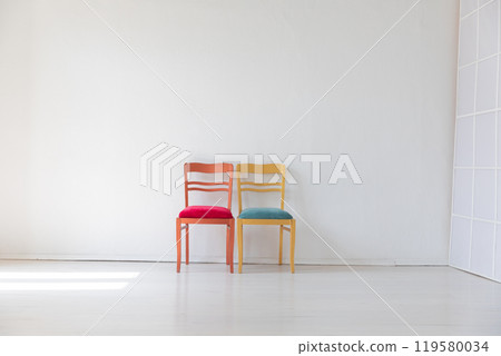 two vintage chairs in the interior of an empty white room with a window 119580034