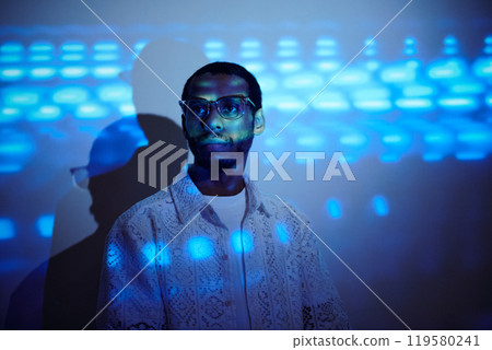 Portrait of Man Wearing Glasses Standing with Blue Light Effects Portrait of Man Wearing Glasses Standing with Blue Light Effects 119580241