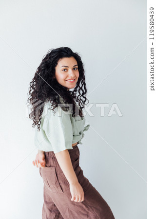 Curly brunette woman in summer clothes smiling Curly brunette woman in summer clothes smiling 119580439