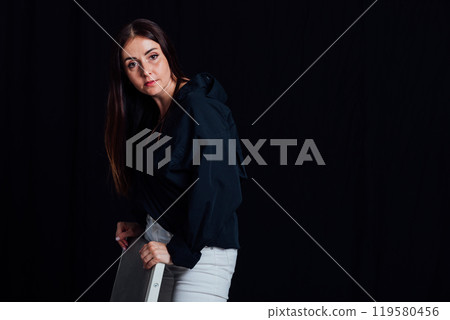 Beautiful fashionable brunette woman posing on black background 119580456