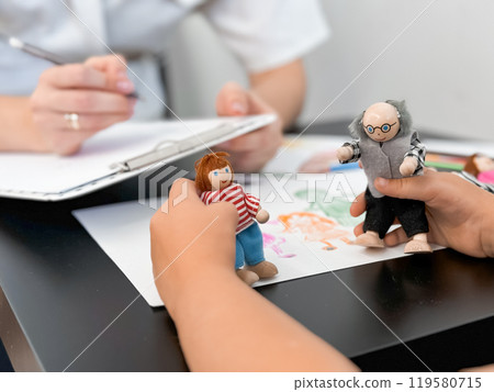 Child therapy session with therapist using puppet play for emotional expression 119580715