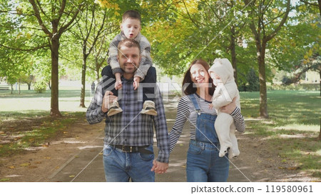 Happy family in the park dad mom and two kids outdoors Happy family in the park dad mom and two kids outdoors 119580961