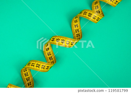Yellow spiral tape measure on green background Yellow spiral tape measure on green background 119581799