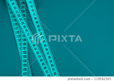 Green tape measure on the bright light green background 119582565