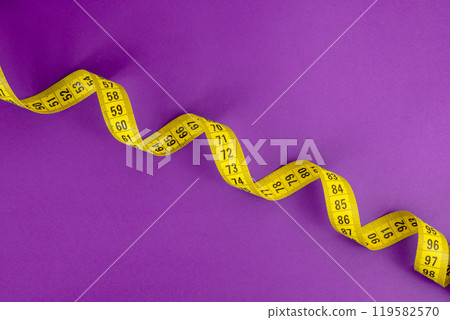 Yellow tape measure on the violet background Yellow tape measure on the violet background 119582570