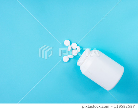 White round pills and bottle on blue background White round pills and bottle on blue background 119582587