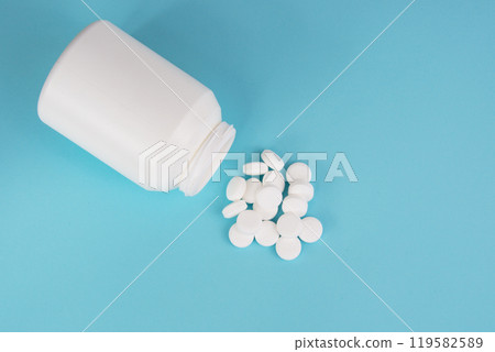 White round pills and bottle on blue background White round pills and bottle on blue background 119582589