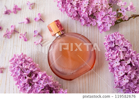 round brown perfume bottle and lilac flowers on wooden background. Mockup, spring summer flat lay. glass perfume bottle for branding and label 119582676