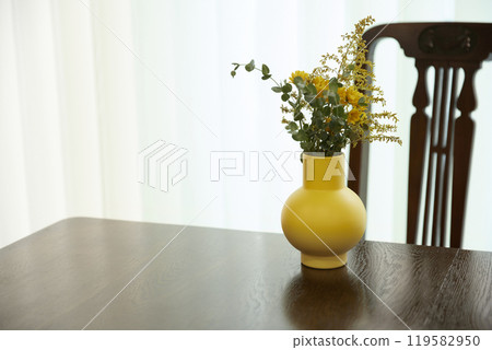 A living room scene with warm sunlight, natural contrast of objects, and relaxed wood tones. 119582950