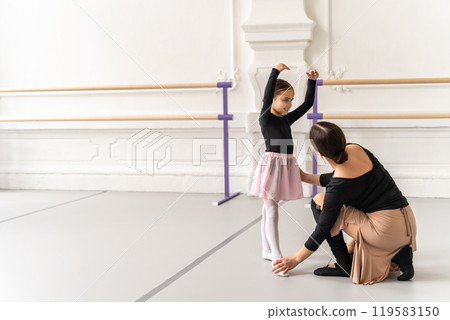 Elegant female trainer coaching young girl in classic ballet lesson Elegant female trainer coaching young girl in classic ballet lesson 119583150