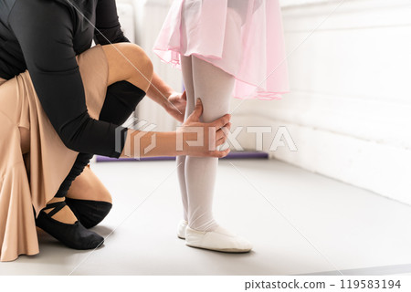Adorable little girl practicing ballet with her female teacher in studio 119583194