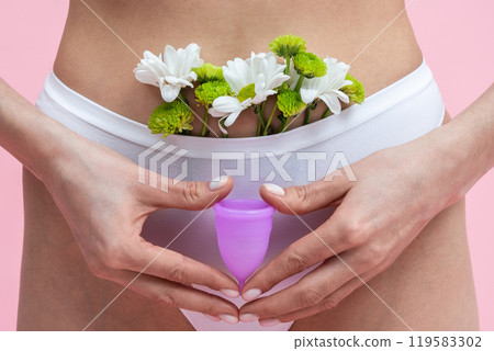 Woman in underwear holding eco-friendly cup standing against pink background Woman in underwear holding eco-friendly cup standing against pink background 119583302