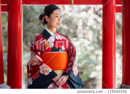 A woman in a kimono visiting a shrine A woman in a kimono visiting a shrine 119583588