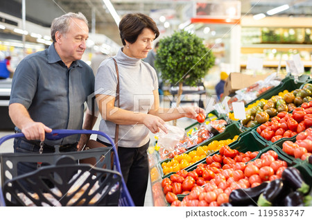 Mature woman and man selecting vegetables in greengrocer 119583747