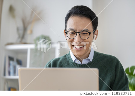 A man in his 40s wearing earphones talking on a laptop A man in his 40s wearing earphones talking on a laptop 119583751
