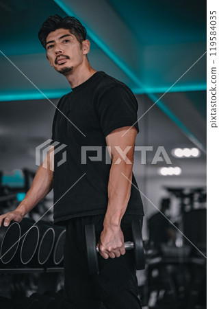 Man holding dumbbells at the gym Man holding dumbbells at the gym 119584035