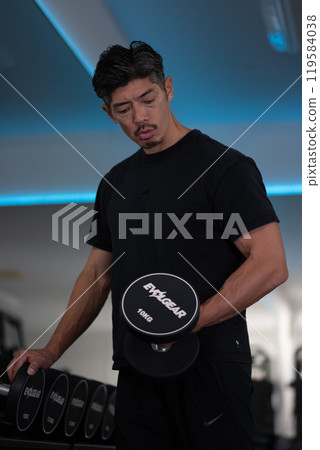 一個男人在健身房拿著啞鈴 119584038