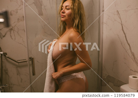 Passionate sexy young naked woman takes a shower and covers herself with a towel 119584079