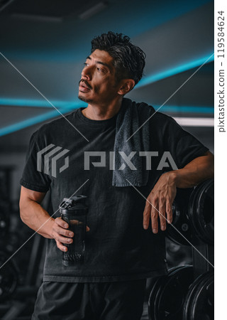 Man taking a break at the gym to hydrate Man taking a break at the gym to hydrate 119584624