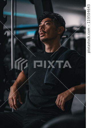 Man taking a break at the gym to hydrate Man taking a break at the gym to hydrate 119584643