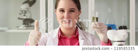 Satisfied laboratory worker shows thumb up holding test tubes Satisfied laboratory worker shows thumb up holding test tubes 119585335