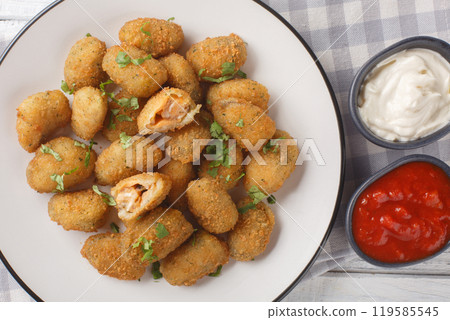 Deep fried breaded mussels served with mayonnaise and ketchup close-up in a plate. Horizontal top view 119585545