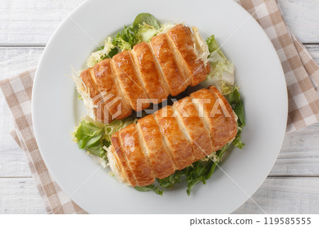 Traditional French Roules au fromage puff pastry tubes with Gruyere cheese and bechamel sauce close-up in a plate. Horizontal top view Traditional French Roules au fromage puff pastry tubes with Gruyere cheese and bechamel sauce close-up in a plate. Horizontal top view 119585555
