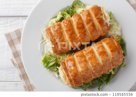 Delicious French puff pastry rolls with gruyere cheese and bechamel sauce close-up in a plate. Horizontal top view Delicious French puff pastry rolls with gruyere cheese and bechamel sauce close-up in a plate. Horizontal top view 119585556