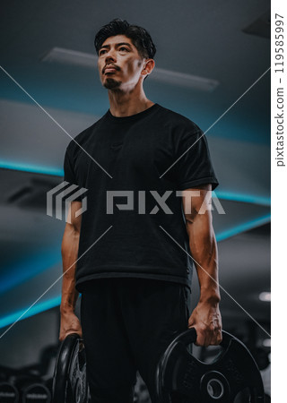 Portrait of a man holding barbell weights at gym Portrait of a man holding barbell weights at gym 119585997