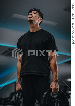 Portrait of a man holding barbell weights at gym Portrait of a man holding barbell weights at gym 119585998