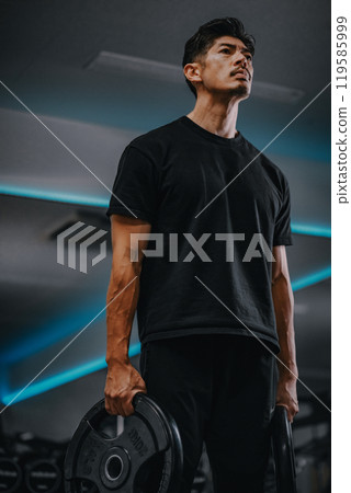 Portrait of a man holding barbell weights at gym Portrait of a man holding barbell weights at gym 119585999