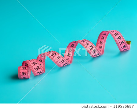 Pink centimeter tape measure on blue background Pink centimeter tape measure on blue background 119586697