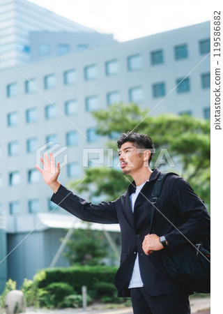 A man stopping a taxi in a business district 119586882